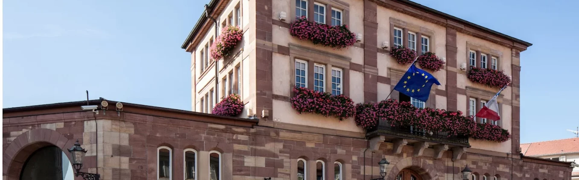 Hôtel de ville de Wasselonne en grès des Vosges avec d'importants balcons fleuris.